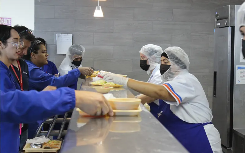 Entrega de alimentos empacados a empleados en comedor industrial